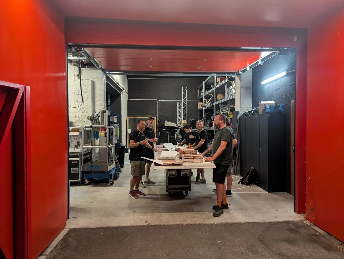 Crew eating pizza off a flight case in a venue loading bay