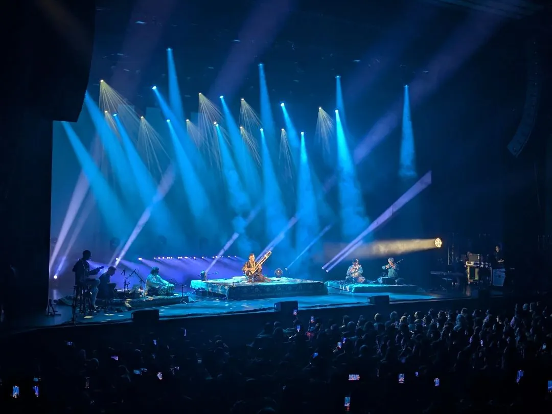 Rishab and band on stage at the Queen Elizabeth Theatre under blue beams