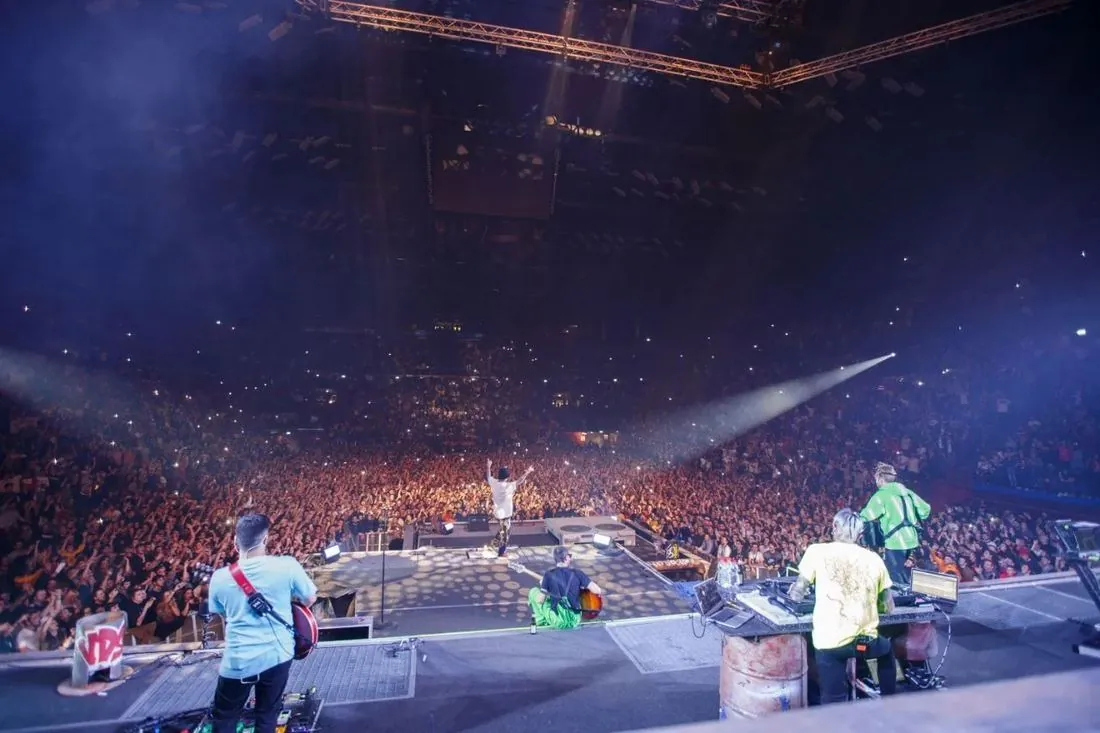 View from the back of the stage over the band to a full arena on Salmo's tour
